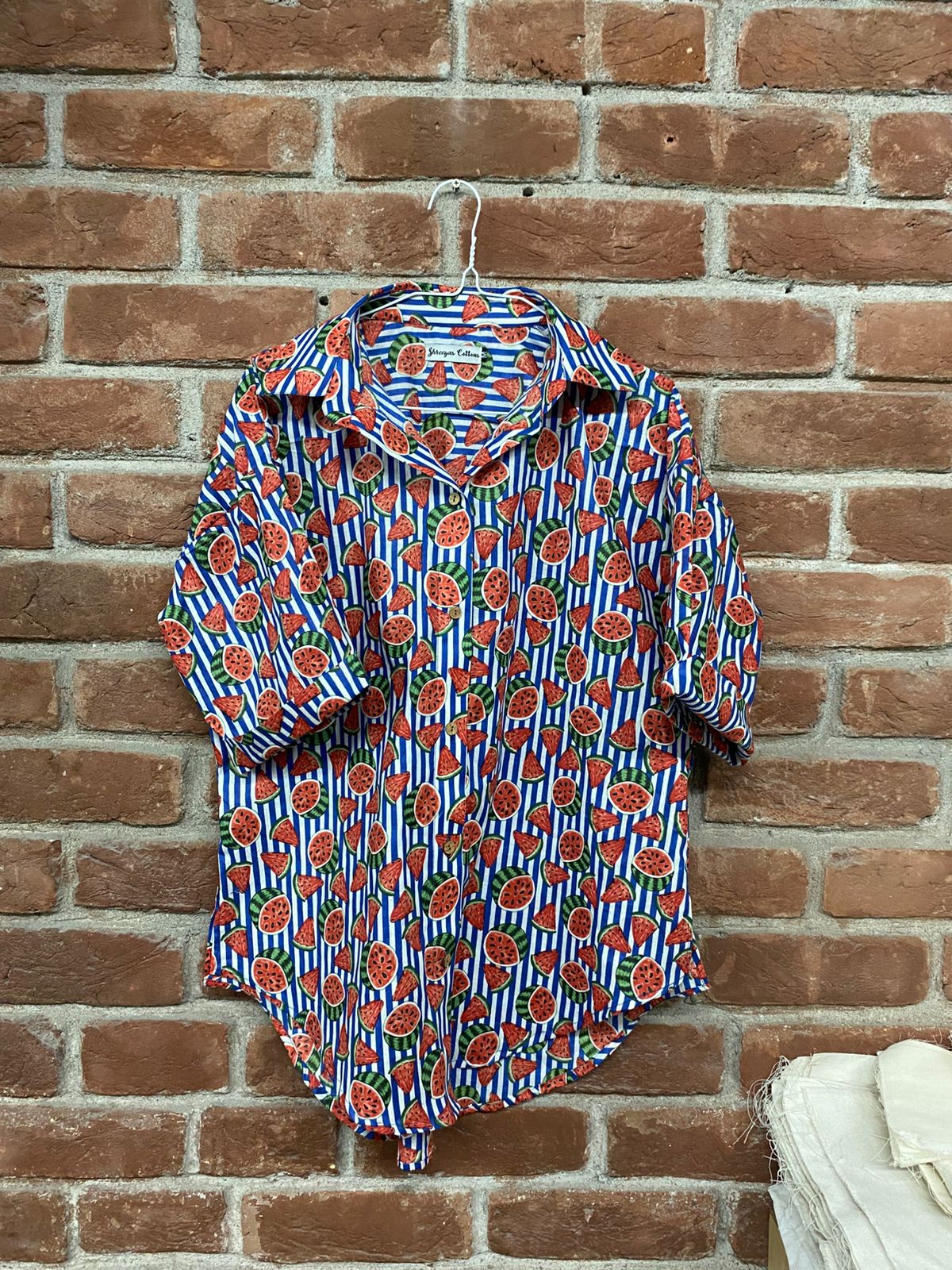Floral patterned shirt on a hanger against a brick wall